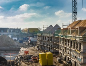 Neubaugebiet mit Baugrube und eingerüsteten halbfertiggestellten Neubauten – Symbolbild für eine Bauherrenhaftpflichtversicherung